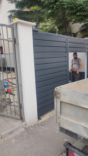 Construction d'une clôture avec des poteaux en béton et des panneaux métalliques au profil moderne thumbnail