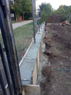 Construction d'un mur de clôture en béton avec des lattes métalliques gris anthracite, portes et allée piétonne thumbnail