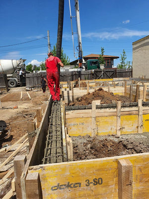 Construction d'une maison de plain-pied, coulée de béton dans les poutres de fondation thumbnail