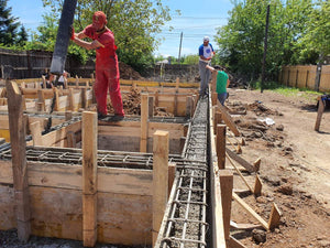 Construction d'une maison de plain-pied, coulée de béton dans les poutres de fondation thumbnail