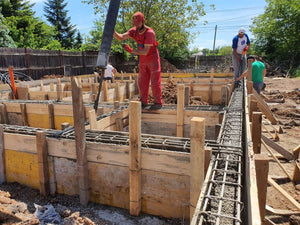 Construction d'une maison de plain-pied, coulée de béton dans les poutres de fondation thumbnail