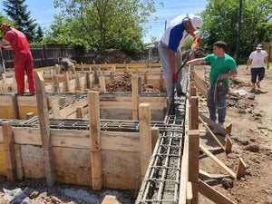 Construction d'une maison de plain-pied, coulée de béton dans les poutres de fondation thumbnail