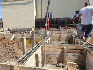 Construction d'une maison de plain-pied, coulée de béton dans les poutres de fondation thumbnail