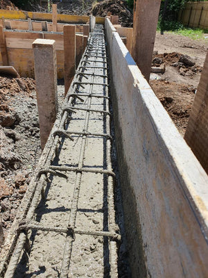 Construction d'une maison de plain-pied, coulée de béton dans les poutres de fondation thumbnail